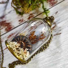 a glass jar filled with dried flowers on top of a wooden table next to a chain