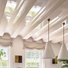 a kitchen with white walls and wooden flooring next to two windows covered in curtains