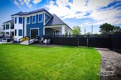 a blue house with a black fence and green grass on the lawn in front of it