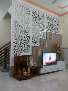 a flat screen tv sitting on top of a wooden stand next to a stair case