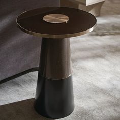 a black and gold side table sitting on top of a carpeted floor next to a couch