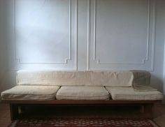 a white couch sitting on top of a wooden floor next to a red and white rug