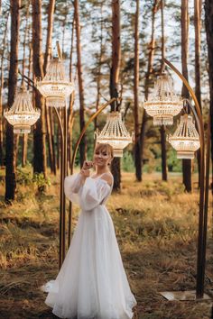 a woman in a white wedding dress standing under chandeliers