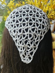 a woman with long hair wearing a white crochet hat and yellow flowers in the background