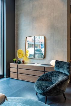 a living room with a blue chair and a large mirror