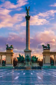 the monument is surrounded by statues on both sides and in front of a blue sky with white clouds