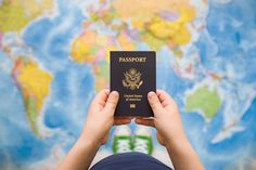 a person holding up a passport in front of a map