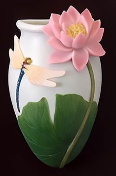 a white vase with a pink flower and dragonfly on the side, against a black background