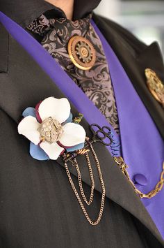 a close up of a person wearing a suit and tie with a flower on the lapel