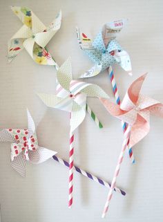 three paper pinwheels and two drinking straws on a table