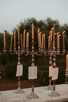 many candles are lined up on a table with notes attached to the candle holders that hold them