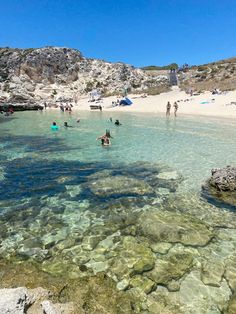 people are swimming in shallow water at the beach