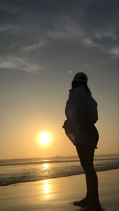 a woman standing on top of a beach next to the ocean