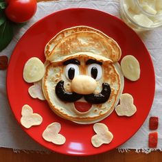 a red plate topped with pancakes covered in toppings and a face drawn on top of it