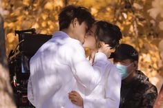 a man and woman kissing each other in front of a cameraman wearing a face mask