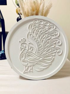 a white plate with a peacock design on it sitting on a table next to some wine bottles