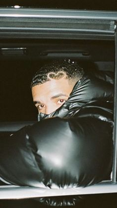 a man wearing black leather gloves in the back of a car with his head out