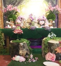 the table is decorated with pink flowers and greenery, along with two stumps