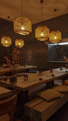 an empty restaurant with wooden tables and stools, lights hanging from the ceiling over them