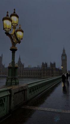 people are walking across the bridge on a rainy day in london, england with big ben in the background