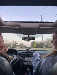 two women sitting in the driver's seat of a car