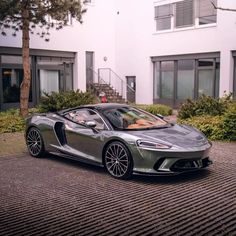 a grey sports car parked in front of a building with stairs leading up to it