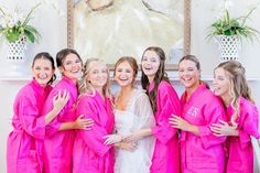 a group of women in pink robes standing next to each other and smiling at the camera