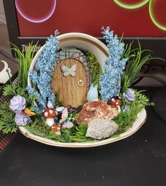 a bowl that has some plants and rocks in it with a fairy door on the inside