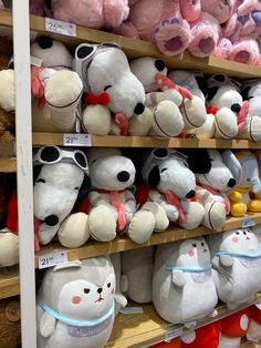 many stuffed animals are on shelves in a toy store, one is white and the other is pink