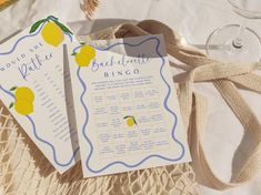 two cards with lemons on them sitting next to some wine glasses and other items