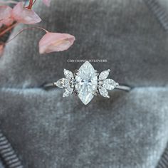 an engagement ring sitting on top of a velvet bag next to flowers and a plant