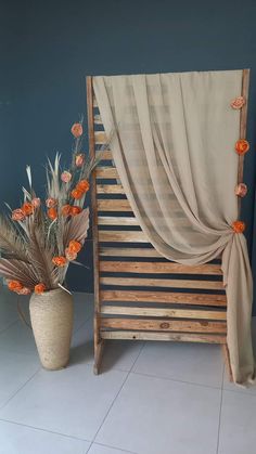 a vase with flowers sitting next to a wooden bed frame and drapes on it