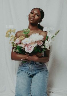 a woman is holding flowers in her hands and posing for the camera with white background