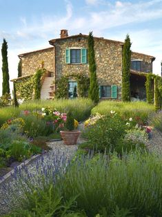 an old stone house surrounded by flowers and greenery