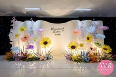 an image of a wedding stage set up with flowers on the side and lights in the background