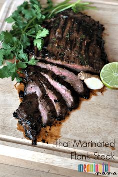 sliced steak with cilantro and parsley on cutting board next to lime wedge