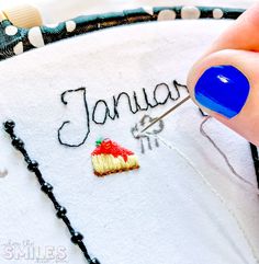 someone is stitching the word january on a piece of fabric with a sewing needle