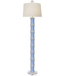 a blue and white floor lamp with a light shade on the top, in front of a