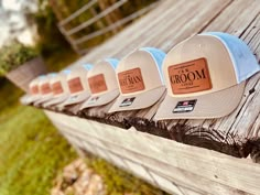 five hats are lined up on a wooden bench in front of some grass and trees