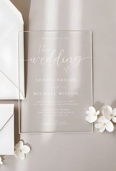 the wedding stationery is displayed with white flowers and an elegant foiled card that reads,