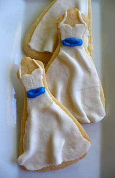 two decorated cookies with white frosting and blue ribbon on them are sitting on a plate