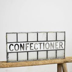 a wooden bench with a sign that says confectioner on the glass block