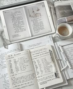 an open book sitting on top of a table next to a cup of coffee and other items