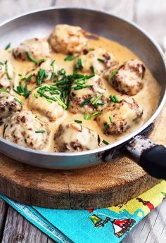 a pan filled with meatballs covered in gravy on top of a wooden board