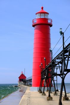 a red light house sitting next to the ocean