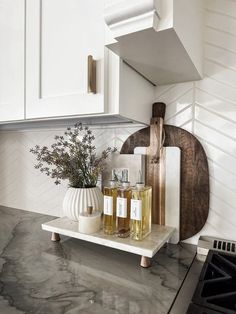 two bottles of liquid sitting on top of a counter next to a cutting board and knife