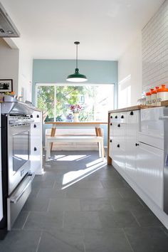 a kitchen with an oven, stove and table in the middle of it's floor