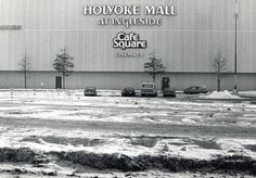 black and white photograph of an outside cafe square with cars parked in the parking lot