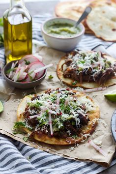 two pita breads with meat, cheese and vegetables on them sitting on a table