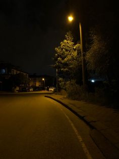 an empty street at night with the lights on and no cars parked in front of it